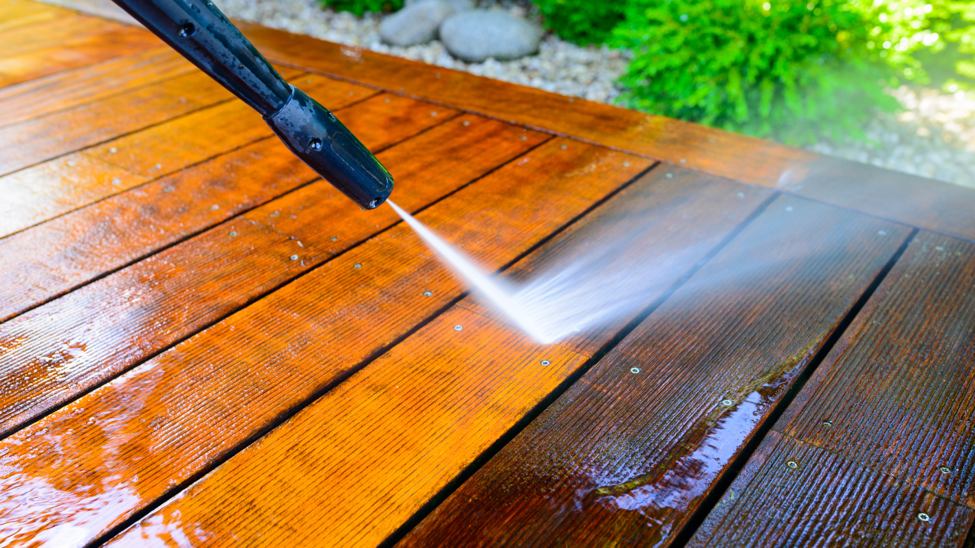 A person spraying water on a wooden deck